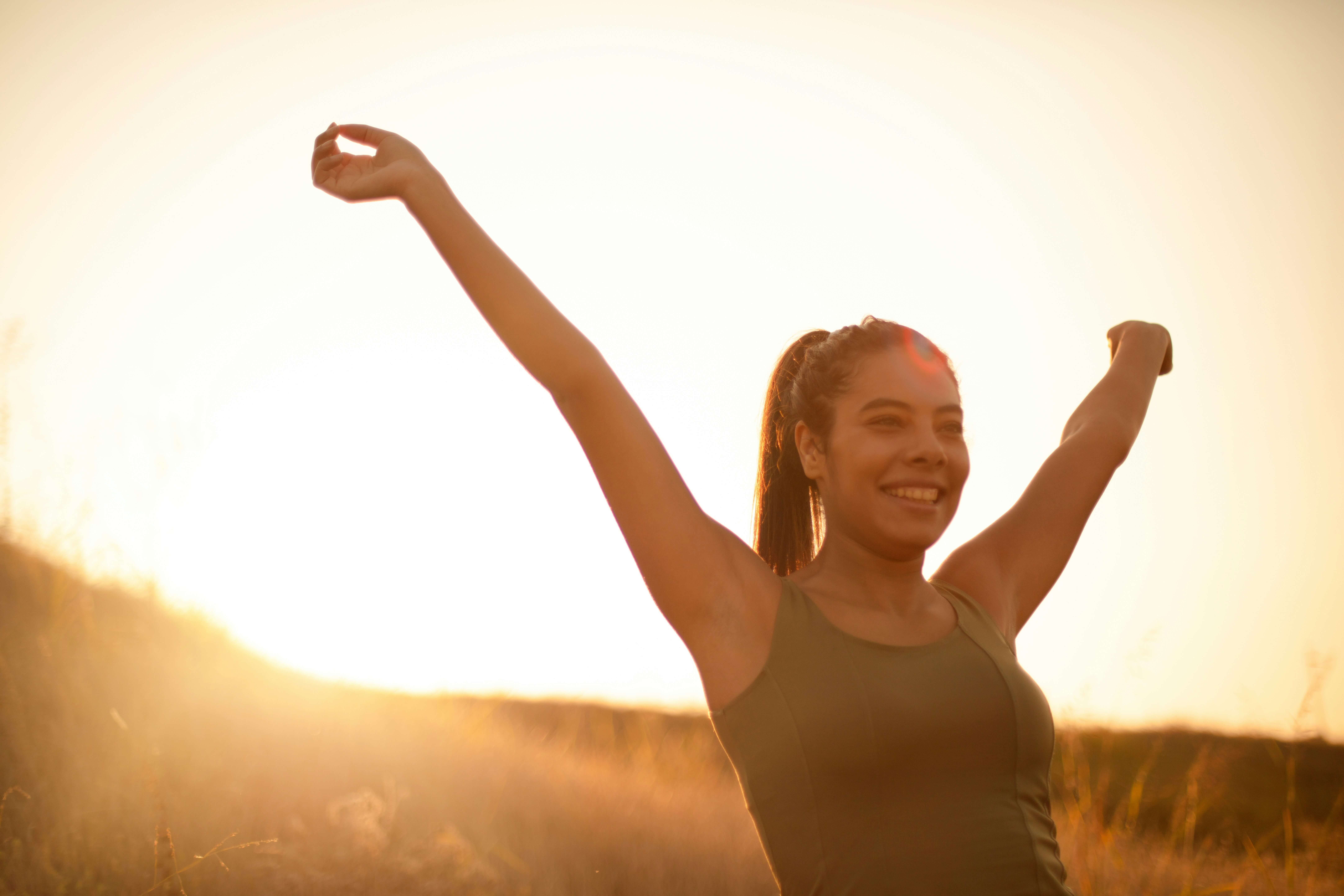 Woman outside in nature spreading her arms wide celebrating mindfulness and clear thinking.